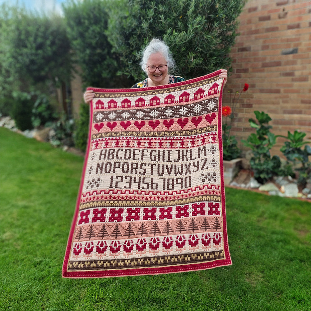 Rosina Plane Lakenham Mosaic Sampler CAL Haakpakket - Vintage deken vastgehouden in de tuin