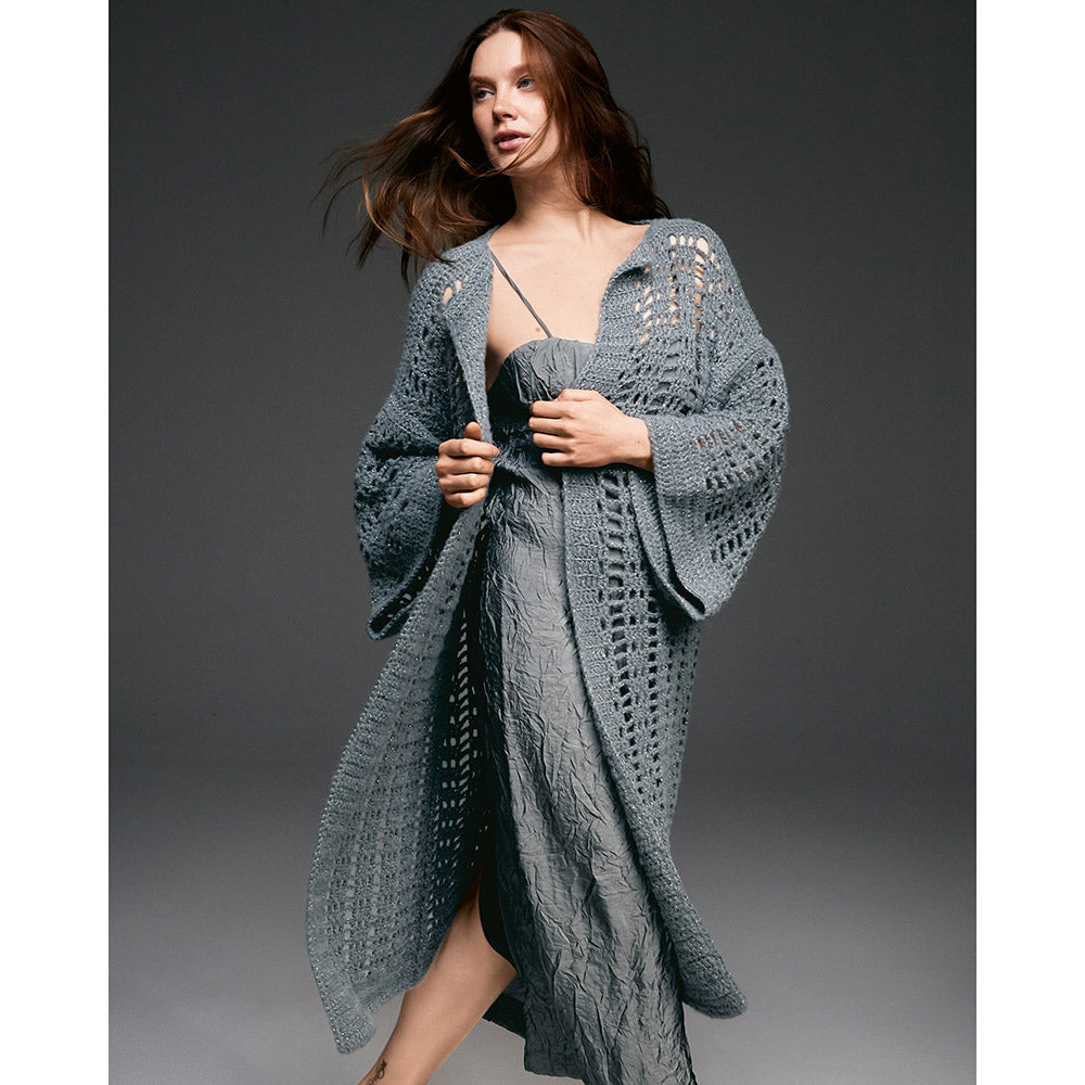 Lana Grossa Brillino sfeerfoto - vrouw draagt een ruimvallende grijze gebreide poncho met glanzend detail